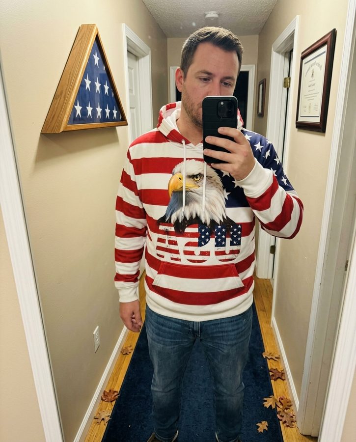 Man in a blue eagle print Veterans Day hoodie taking a mirror selfie
